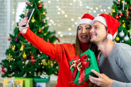 Photo for A young couple is celebrating their Christmas together happily at home. - Royalty Free Image