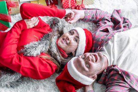 Photo for A young couple is celebrating their Christmas together happily at home. - Royalty Free Image