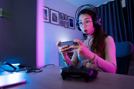 Photo for Asian modern female gamer having serious gaming fun in a RGB-lit gaming room. - Royalty Free Image