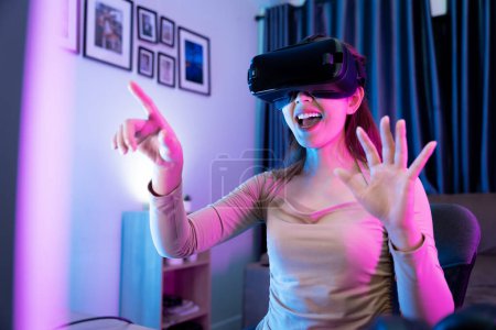 Téléchargez les photos : Asiatique moderne gamer féminin avoir du plaisir à jouer à des jeux de la console VR dans la salle de jeu RGB. - en image libre de droit