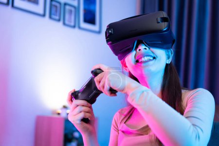 Photo for Asian modern female gamer having serious fun playing games from VR console in RGB gaming room. - Royalty Free Image