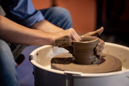 Téléchargez les photos : Faïence L'art de sculpter l'argile avec de la céramique moulée à la main sur une machine à filer. avec la bonne posture pour créer une assiette ou un vase professionnellement - en image libre de droit