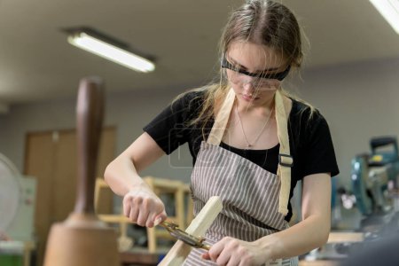 Téléchargez les photos : Portrait d'une menuisière utilisant des outils de meubles dans une usine de meubles. elle utilise une raboteuse rabotage avec du bois utilisé pour créer des meubles avec des outils modernes - en image libre de droit