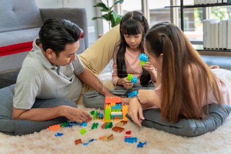 Téléchargez les photos : Portrait de famille asiatique Il ya des parents et des filles jouant puzzles bloc à la maison ensemble avoir du plaisir et du bonheur. - en image libre de droit