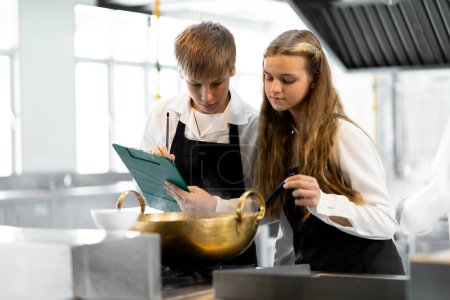 Téléchargez les photos : Les étudiants apprennent à cuisiner dans un institut culinaire avec une cuisine standard et un équipement complet. Et avoir un chef professionnel comme formateur. - en image libre de droit