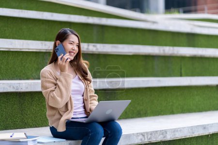 Photo for Asian female student Studying for exams in the area of the university. Communicate via mobile phone or laptop connected to the Internet. with many sources of knowledge - Royalty Free Image