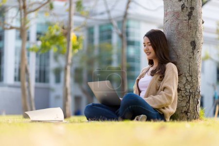 Photo for Asian female student Studying for exams in the area of the university. Communicate via mobile phone or laptop connected to the Internet. with many sources of knowledge - Royalty Free Image