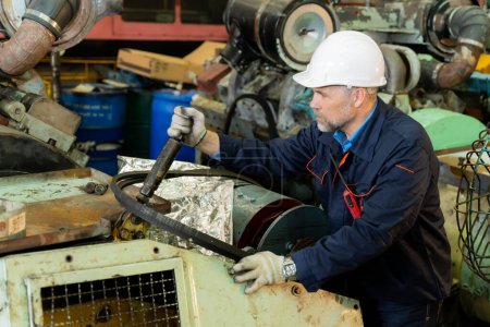 Photo for A machine factory engineer is inspecting the machines in the factory with a tablet or laptop and with a deliberate eye check. The factory is big and old. - Royalty Free Image
