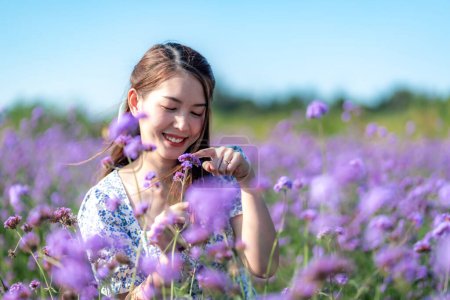 Foto de Retrato de una alegre mujer tailandesa asiática en un jardín de flores púrpura. - Imagen libre de derechos