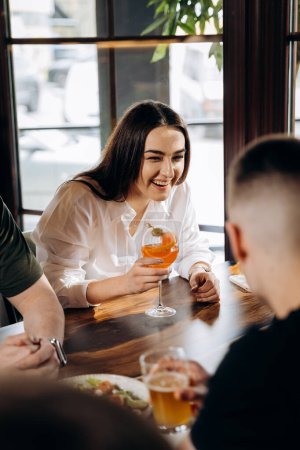 Photo for Young smiling woman enjoying a coctail in bar restaurant during rest with friends.  Celebration and party concept - Royalty Free Image