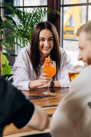 Photo for Young smiling woman enjoying a coctail in bar restaurant during rest with friends - Royalty Free Image