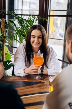 Photo for Young smiling woman enjoying a coctail in bar restaurant during rest with friends - Royalty Free Image