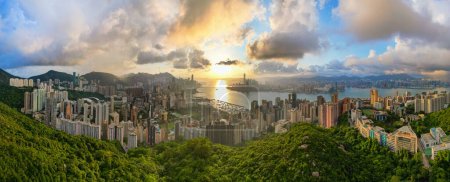 Top aerial view of Hong Kong skyline and cityscape with sunset. Amazing panorama of highrise buildings and modern towers and sky reflecting in the harbor. Hong Kong island and Kowloon landside.