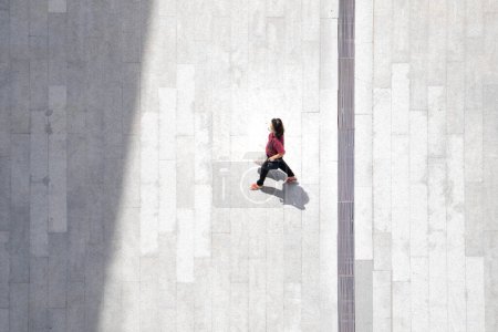 Téléchargez les photos : Top vue aérienne femme gens marchent sur le béton piéton avec silhouette noire ombre sur le sol, concept de nature morte sociale. - en image libre de droit