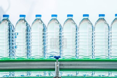 Téléchargez les photos : Beaucoup de bouteilles d'eau minérale dans l'usine de boissons. les bouteilles d'eau potable en plastique transparent placées sur la ligne de production. - en image libre de droit