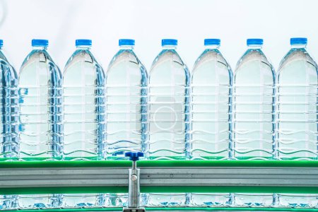 Foto de Muchas botellas de agua mineral en la fábrica de bebidas. las botellas de plástico transparente de agua potable lugar en la línea de producción. - Imagen libre de derechos