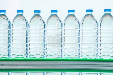 Foto de Muchas botellas de agua mineral en la fábrica de bebidas. las botellas de plástico transparente de agua potable lugar en la línea de producción. - Imagen libre de derechos