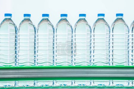 Téléchargez les photos : Beaucoup de bouteilles d'eau minérale dans l'usine de boissons. les bouteilles d'eau potable en plastique transparent placées sur la ligne de production. - en image libre de droit