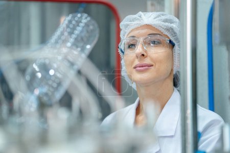 Photo for Factory woman engineer inspecting water dispenser on the machine. The worker checks the quality of water bottles on the machine conveyor line at the industrial factory. - Royalty Free Image
