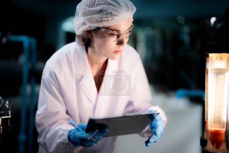 Photo for Scientist worker checking the quality of Reverse osmosis machine system at the industrial factory. Female worker recording data at the control panel with measure pressure for recycle portable plant. - Royalty Free Image