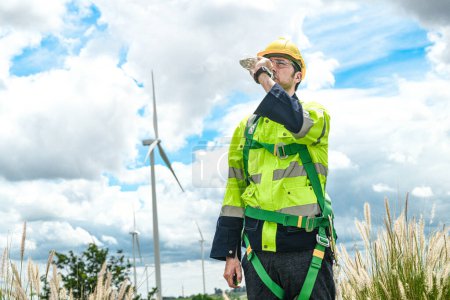 Photo for Worker drinking water. Technicians of wind turbine checking and maintenance Electricity wind generator.. operation of wind turbines that convert wind energy into electrical energy - Royalty Free Image