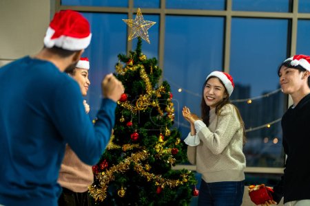Téléchargez les photos : Groupe d'amis asiatiques célébrant et dansant avec l'éclairage. Fête des belles femmes et des hommes célébrant. Heureux amis fête de Noël dîner dans la maison avec des arbres de Noël. - en image libre de droit