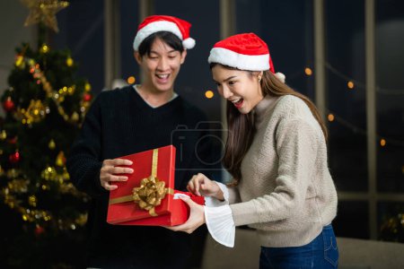 Téléchargez les photos : Partie de beau couple asiatique féminin et masculin célébrant. amoureux du bonheur Noël célébration boîte d'ouverture cadeau et présent ensemble dans le salon. - en image libre de droit