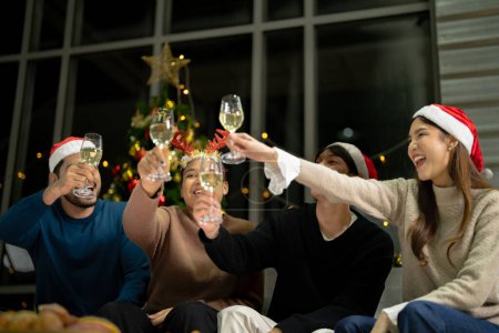 Téléchargez les photos : Fermer les verres de verres de champagne cliquetis avec éclairage. Partie de l'ami asiatique femelle et mâle célébrant. amis bonheur réveillon de Noël célébrer le dîner avec de la nourriture et du champagne. - en image libre de droit