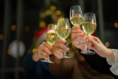 Photo for Close up glasses of clinking glasses of champagne with lighting. Dinner party with drinking of champagne. hands holding clear glass with alcohol in yellow shine reflect. - Royalty Free Image