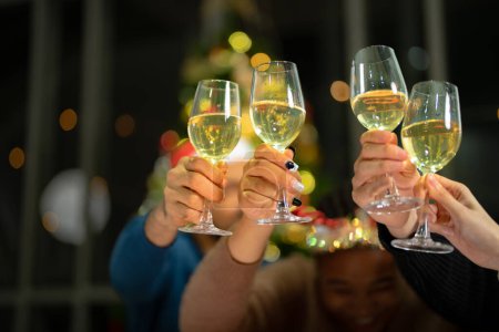 Photo for Close up glasses of clinking glasses of champagne with lighting. Dinner party with drinking of champagne. hands holding clear glass with alcohol in yellow shine reflect. - Royalty Free Image