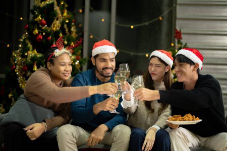 Téléchargez les photos : Fermer les verres de verres de champagne cliquetis avec éclairage. Partie de l'ami asiatique femelle et mâle célébrant. amis bonheur réveillon de Noël célébrer le dîner avec de la nourriture et du champagne. - en image libre de droit
