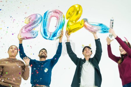 Foto de Grupo de personas que sostienen globos de colores de fantasía burbuja del número 2024 para el nuevo año. hombres y mujeres de pie sobre un fondo blanco. celebración de la fiesta feliz año nuevo - Imagen libre de derechos