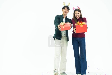 Téléchargez les photos : Jeune couple asiatique deux amis homme femme portant des vêtements décontractés et tenant cadeau boîte rouge avec des cadeaux ensemble isolé sur fond blanc portrait studio. concept nouvelle année et cadeaux de Noël. - en image libre de droit