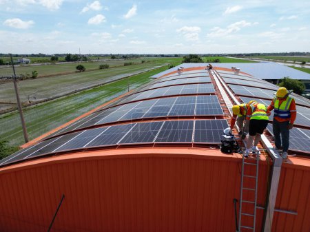 Téléchargez les photos : Ingénieur homme inspecte la construction de panneaux solaires ou de cellules photovoltaïques sur le toit. Énergie renouvelable industrielle de l'énergie verte. usine en zone urbaine. travailleur travaillant sur le toit de la tour. - en image libre de droit