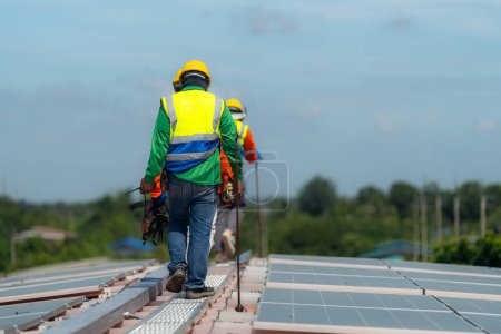 Téléchargez les photos : Les Techniciens Travailleurs travaillent à la construction de panneaux solaires sur le toit. Installation de panneaux solaires photovoltaïques. Concept écologique d'énergie alternative. Concept de technologie des énergies propres renouvelables. - en image libre de droit