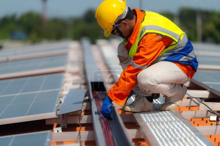 Téléchargez les photos : Les Techniciens Travailleurs travaillent à la construction de panneaux solaires sur le toit. Installation de panneaux solaires photovoltaïques. Concept écologique d'énergie alternative. Concept de technologie des énergies propres renouvelables. - en image libre de droit
