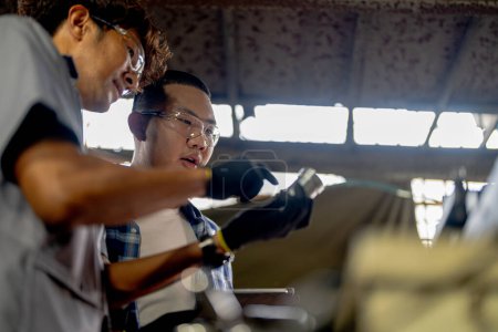 Photo for Men are inspecting steel parts for machine installation. team of teacher and student are learning to use heavy machines in steel factory. workers cooperate while doing quality control of manufactured. - Royalty Free Image