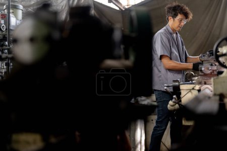Téléchargez les photos : Travailleur asiatique dans le forage de l'usine de production à la machine. Travailleur professionnel près de la machine de forage sur l'usine. finition métal travail surface interne en acier sur tour rectifieuse avec étincelles volantes. - en image libre de droit