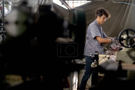 Photo for Asian worker in production plant drilling at machine. Professional worker near drilling machine on factory. finishing metal working internal steel surface on lathe grinder machine with flying sparks. - Royalty Free Image