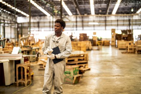 Téléchargez les photos : Travailleurs africains ingénierie debout avec confiance avec robe de suite de travail et gants de main dans la machine avant. Concept de travailleur de l'industrie intelligente opérant. Bois usine produire bois palais. - en image libre de droit