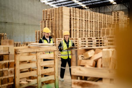 Photo for Workers man and woman engineering walking and inspecting timbers wood in warehouse. Concept of smart industry worker operating. Wood factories produce wood palate. - Royalty Free Image