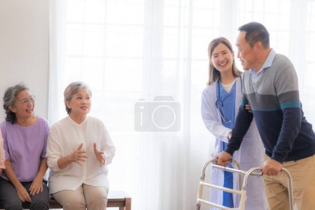 Téléchargez les photos : Asiatique jeune infirmière soutenir homme âgé marcher avec marcheur. Belle infirmière aider et prendre soin. grand-père mature âgé patient faisant de la physiothérapie avec un groupe d'amis âgés à l'hôpital. - en image libre de droit