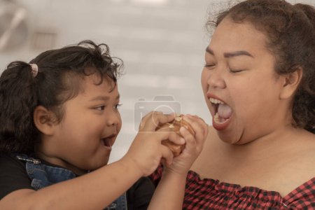 Photo for Close up face of a Cute Asian girl eating a snack with family. Pretty Black Child Eating Snack At Home. Preschool Kid Having A Bite With Fresh Baked Biscuits. - Royalty Free Image