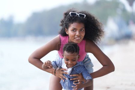 Foto de Raza mixta Africana y Asiática madre y niño está jugando en el área al aire libre. sonriente familia feliz divertirse corriendo en la playa. retrato de la mamá y el estilo de vida del niño con un peinado único. - Imagen libre de derechos