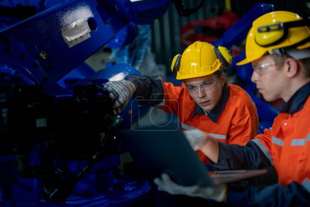 Photo for Factory engineers inspecting on machine with smart tablet. Worker works at heavy machine robot arm. The welding machine with a remote system in an industrial factory. Artificial intelligence concept. - Royalty Free Image