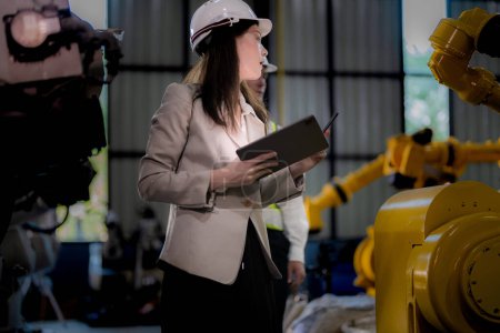 Photo for Business woman and man meeting and checking new machine robot. Engineer walking at warehouse industry machine. business negotiation concepts and technology. woman is Using smart Tablet to present man. - Royalty Free Image