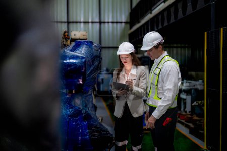 Photo for Business woman and man meeting and checking new machine robot. Engineer walking at warehouse industry machine. business negotiation concepts and technology. woman is Using smart Tablet to present man. - Royalty Free Image