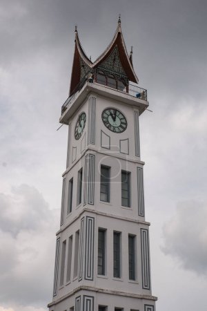 Téléchargez les photos : Grande horloge d'interdiction au milieu de la place avec un ciel nuageux ", confiture gadang bukit tinggi" - en image libre de droit