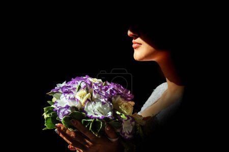 Téléchargez les photos : Photo de mariage créative d'une mariée avec un bouquet de fleurs, contraste de lumière et d'ombre, aiguille sur fond noir, lumière sur la moitié du visage - en image libre de droit