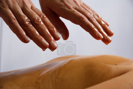 las manos de la masajista en el aceite el aceite que gotea de los dedos